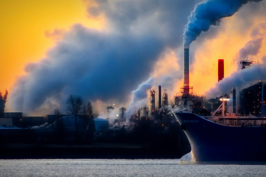 Chemical Contamination in waterA large boat on a water surface Infront of several factories with tall chimney chutes