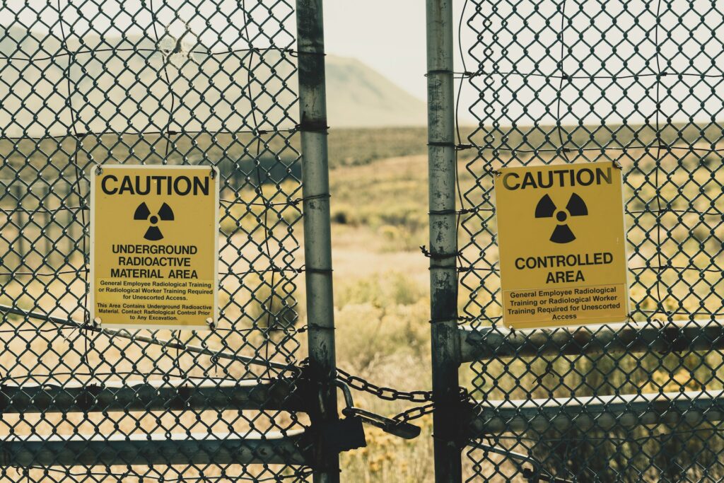 What are the dangers of radioactive contamination in water? Wire fence with radiation hazard signs
