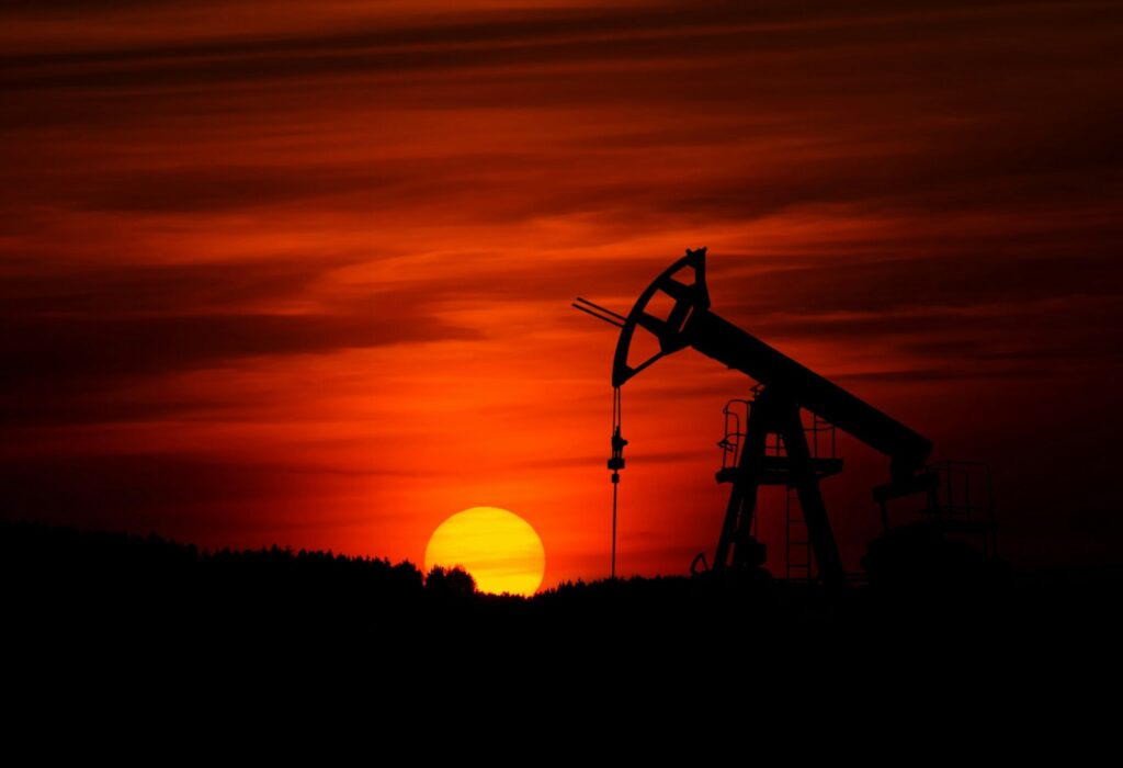 The Dangers of Hydrocarbon Contamination in Drinking Water, An oil drill Infront of a crimson sky, with the sun setting over the horizon.